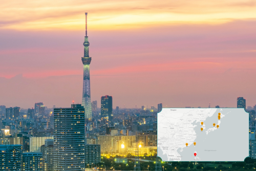 Stadtansicht von Tokio bei Sonnenuntergang mit dem beleuchteten Tokyo Skytree im Zentrum; im Vordergrund dichte Hochhäuser, im Hintergrund ein orange-rosa Himmel. Unten rechts ist eine kleine Karte von Japan eingeblendet, auf der mehrere markierte Punkte die Route der Kreuzfahrt darstellen. Stadtansicht von Tokio bei Sonnenuntergang mit dem beleuchteten Tokyo Skytree im Zentrum; im Vordergrund dichte Hochhäuser, im Hintergrund ein orange-rosa Himmel. Unten rechts ist eine kleine Karte von Japan eingeblendet, auf der mehrere markierte Punkte die Route der Kreuzfahrt darstellen.